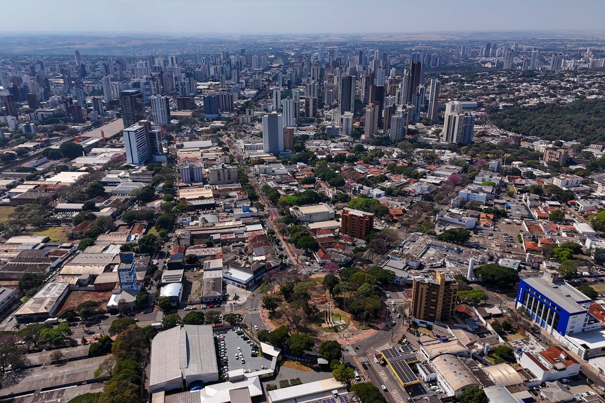 Vista aérea de Maringá mostrando a malha urbana arborizada, com prédios ao fundo e ruas largas