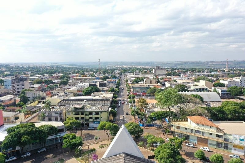 Vista aérea de Sarandi mostrando a avenida principal, o comércio de rua e a região urbana com o horizonte de plantações ao fundo