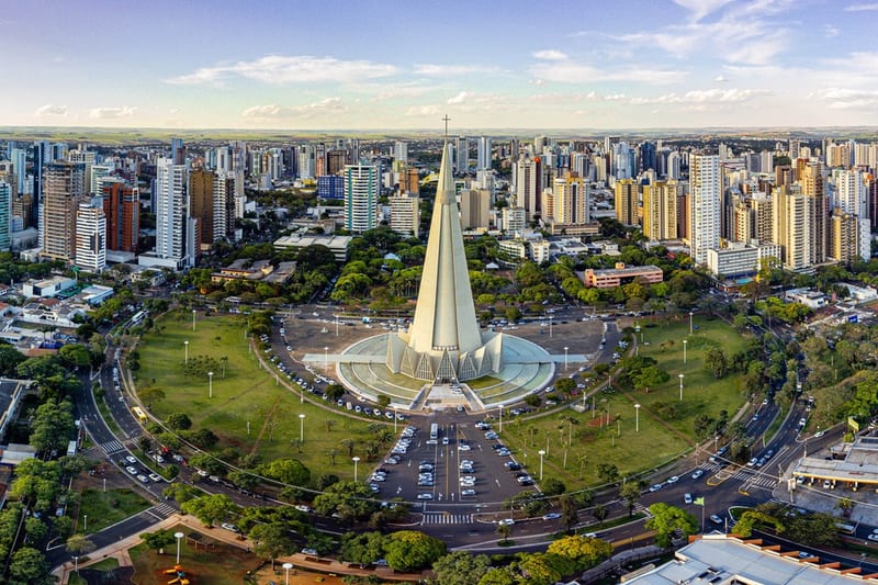 Vista aérea de Maringá com a Catedral no centro, rodeada pelo anel viário, gramado e prédios ao fundo